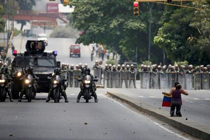 Una manifestante se arrodilla frente a miembros de la policía antidisturbios durante la protesta contra el gobierno de Nicolás Maduro, en Caracas (Venezuela).