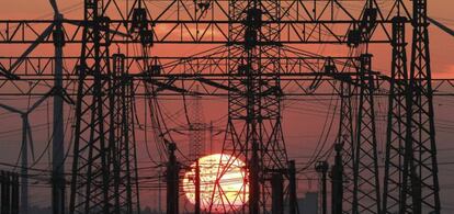En la imagen, una puesta de sol junto al tendido eléctrico y unos molinos de viento (izq).
