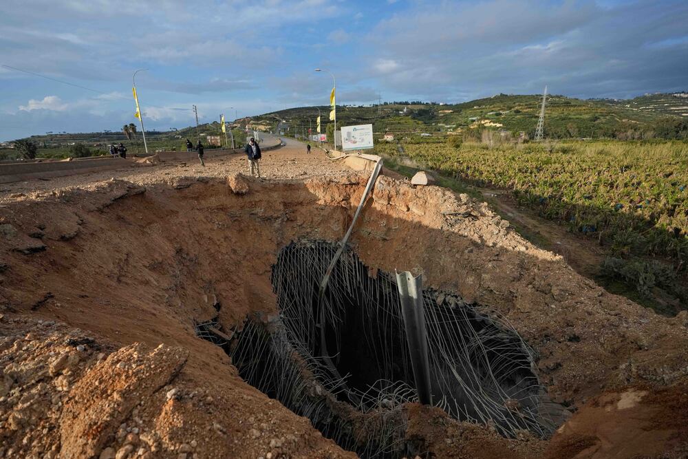 People inspect a crater following an Israeli airstrike that hit the Qasmiyeh Bridge near the coastal city of Tyre, Lebanon, Sunday, March 22, 2026. (AP Photo/Mohammad Zaatari)