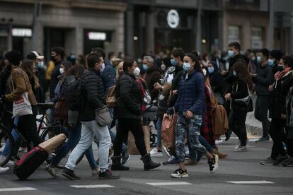 Desenes de persones travessen el pas de vianants que comunica la plaça de Catalunya amb la Rambla, a Barcelona.