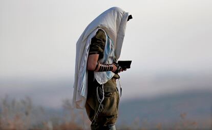 Un soldado israelí reza a primera hora de la mañana en los alrededores de la ciudad israelí de Sderot, junto a la Franja de Gaza.