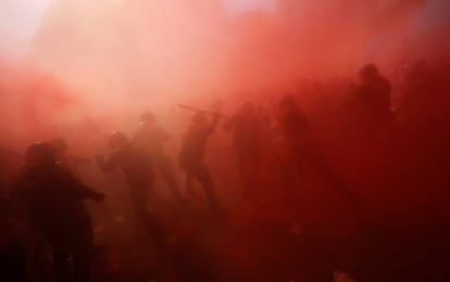 Manifestantes y agentes de Mossos d'Esquadra envueltos en una nube de polvo.