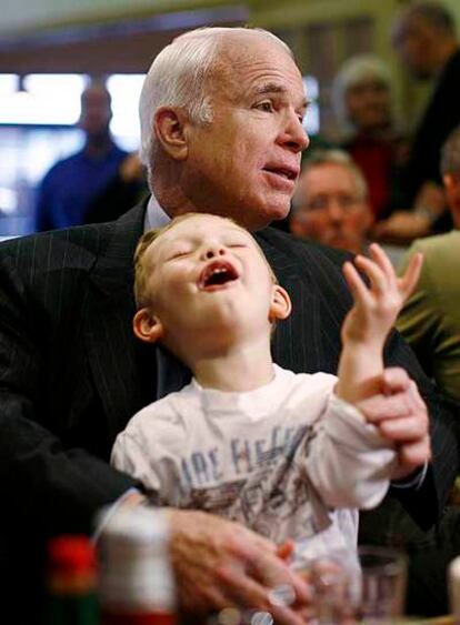 El republicano John McCain, con un niño en brazos, ayer en Florida.
