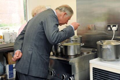 El príncipe de Gales huele una sopa casera en una visita a una granja comunitaria.