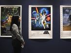 Una empleada de Sothebys observa unos carteles originales de las primeras películas de Star Wars que pondrá a subasta.