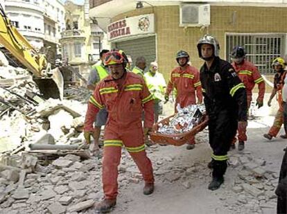 Los bomberos de Alzira retiran el cadáver de la mujer fallecida en el derrumbamiento.