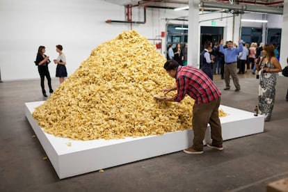 Un visitante se sirve patatas fritas de una instalación durante una muestra de la artista de arte comestible Jennifer Rubell.