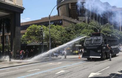 Veículo antiprotesto lança água contra manifestantes.