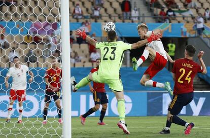 Karol Swiderski de Polonia salta por el balón mientras sufre la presión de Unai Simon.