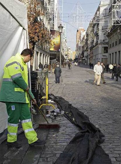 Un empleado de los servicios de limpieza barre la calle de Preciados de Madrid en la mañana del 1 de enero.