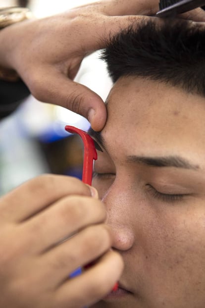 Detalle de uno de los clientes de la barbería New York al que le están afeitando las cejas.