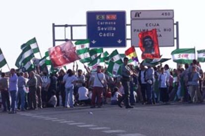 Un grupo de jornaleros bloquea ayer la N-IV a la altura de Écija (Sevilla) en uno de los siete cortes de tráfico del SOC contra la reforma laboral.