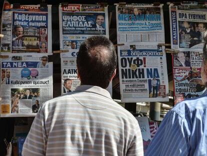 Dos hombres miran los titulares de la prensa griega.