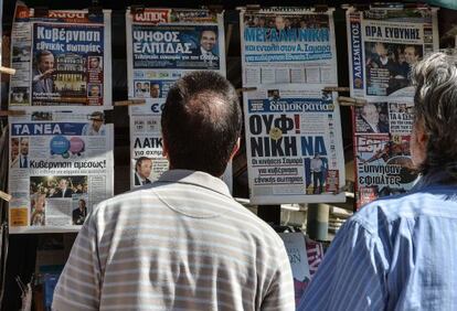 Dos hombres miran los titulares de la prensa griega.