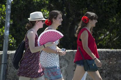 Tres chicas pasean por Sevilla, una de ellas utiliza un abanico para refrescarse.