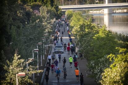 Un coche de la Policía Local de Sevilla circula entre cclistas, corredores y caminantes junto al río Guadalquivir en Sevilla, el 2 de mayo, primer día en el que se permite las salidas para pasear y hacer ejercicio.