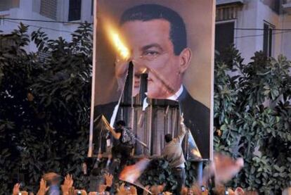 Unos manifestantes arrancan un cartel con la imagen del presidente Hosni Mubarak en Alejandría.
