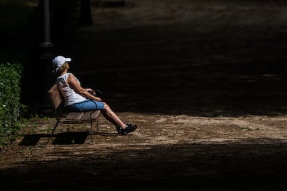 Una mujer toma el sol en un banco del Parque de El Retiro.