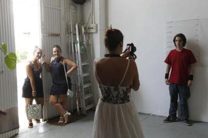 Lola Sopeña, de espaldas, fotografía a un aspirante a figurante, ayer en Sevilla, mientras dos chicas esperan su turno en la puerta.