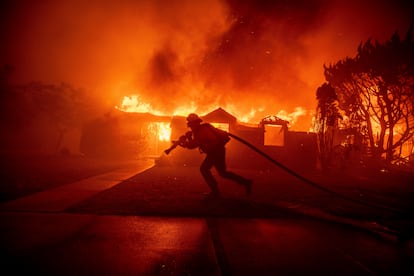 Un bombero trata de sofocar el fuego que arrasa parte del barrio de Palisades en Los Ángeles (California), el pasado 7 de enero.