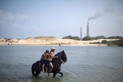 Un israelí monta su caballo con dos niños en el agua en una playa cerca del kibutz Zikim (Israel).