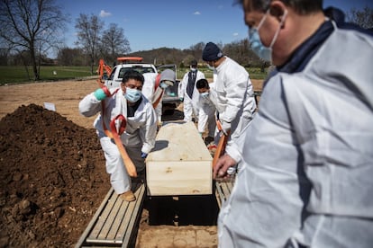 Coveiros baixam o caixão de vítima do coronavírus no cemitério da Associação Hebraica de Enterro Livre no distrito de Staten Island, em Nova York, em abril de 2020.