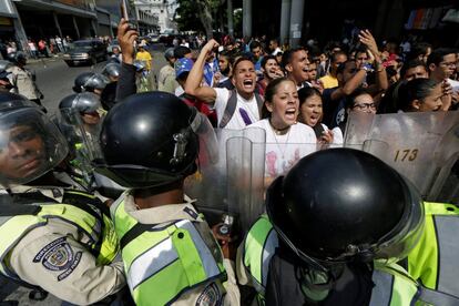 Partidarios de la oposición gritan eslóganes frente a la policía antidisturbios, en Caracas. 