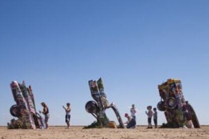 Turistas pintando con spray dos de los diez coches semienterrados que conforman esta instalación artística de Cadillac Ranch, en Amarillo (Texas), en plena Ruta 66.