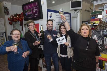 La vendedora de un quinto premio de la loteria de navidad, el número 22259, Carolina Abellán (2d), junto a su madre, dueña del la floristería y ferretería, Mari Carmen Espinosa (d), y su marido, Pedro Francisco Navarro (2i), celebran la venta del número acompañados de vecinos, hoy en Torreagüera (Murcia).