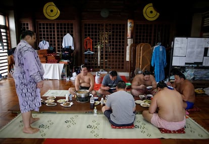 Un grupo de luchadores hace una pausa durante el entrenamiento para comer en la sala principal del templo Ganjoji Yakushido donde se preparan para el torneo Nagoya Grand Sumo.