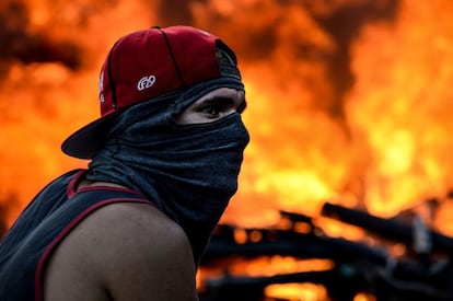 Un manifestante encapuchado permanece junto a una moto en llamas durante una protesta en Caracas, el 22 de junio de 2017.