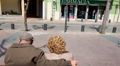 Una pareja de pensionistas ante una farmacia.