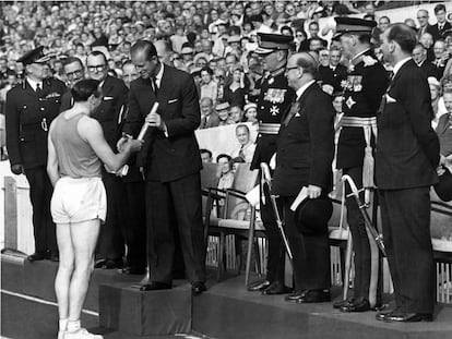 O duque de Edimburgo recebe o bastão que contém a mensagem da rainha das mãos de Ken Jones na abertura dos Jogos do Império e da Commonwealth no estádio Cardiff Arms Park em 18 de julho de 1958.