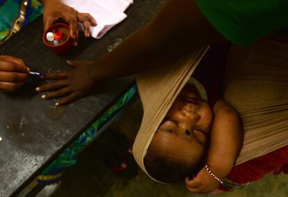 Una mujer india es marcada en su dedo con tinta, mientras su hija duerme, tras votar en una mesa electoral en Chennai, el 18 de abril de 2019. India celebraba la segunda de las siete fases de sus gigantescas elecciones legislativas, las más grandes de la historia, repartidas en cerca de seis semanas por razones logísticas.