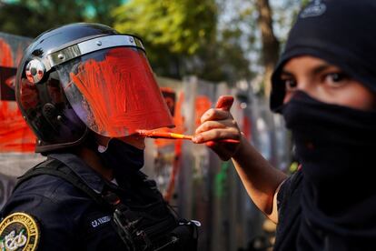 Un miembro de un colectivo feminista pinta el casco de un policía durante una protesta contra la violencia de género y policial, en Ciudad de México (México). Decenas de mujeres se manifestaron este miércoles para protestar contra la violencia policial ocurrida el lunes en Cancún, donde la policía dispersó a disparos una marcha contra los feminicidios.