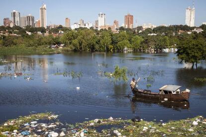 Un hombre rema en un campo de fútbol inundado en el centenario barrio Ricardo Brugada. Al fondo se alzan las torres residenciales y empresariales del microcentro. Asunción, la capital de Paraguay, es un ejemplo de la desigualdad social que lastra al país sudamericano.