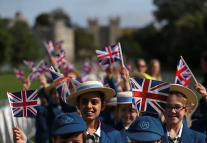 Alumnos de un colegio ondean banderines de Reino Unido en el castillo de Windsor un día antes de la celebración de la boda real. 