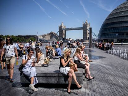 Turistas y ciudadano sen general se toman un descanso cerca de City Hall en el centro de Londres el 2 de julio de 2018