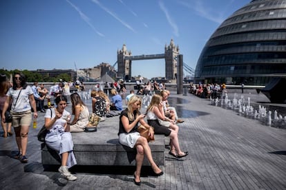 Turistas y ciudadano sen general se toman un descanso cerca de City Hall en el centro de Londres el 2 de julio de 2018