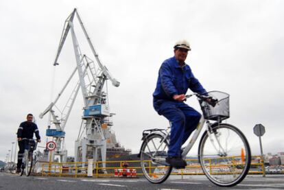 Empleados de Navantia se desplazan el bicicleta en las instalaciones del astillero.