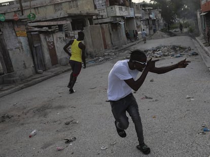 Un pandillero apunta con un arma imaginaria a un rival en una esquina que sirve como divisor entre territorios controlados por pandillas, en el barrio de Bel Air de Port-au-Prince, Haití.