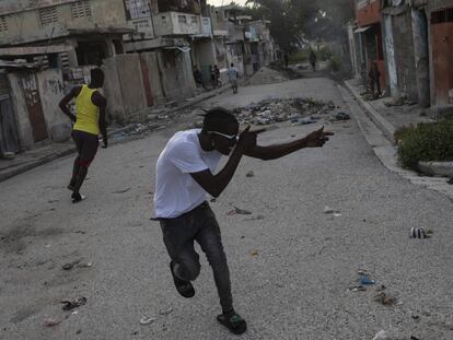 Un pandillero apunta con un arma imaginaria a un rival en una esquina que sirve como divisor entre territorios controlados por pandillas, en el barrio de Bel Air de Port-au-Prince, Haití.