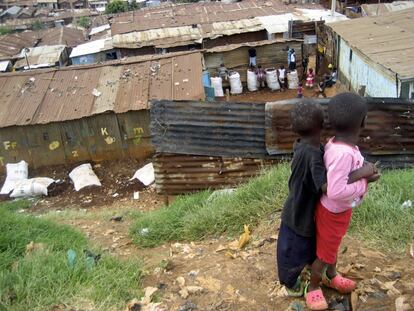 Dos hermanos observan los juegos de sus vecinos en Kibera. Las chancletas son el calzado de millones de personas empobrecidas.