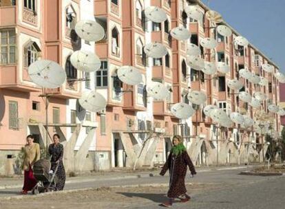 Unas mujeres pasean por delante de un edificio de viviendas plagado de antenas parabólicas en Turkmenabat.