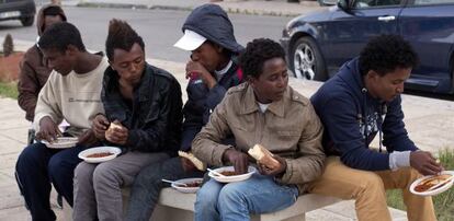 Un grupo de voluntarios ofrece comida a inmigrantes eritreos del centro de internamiento de Lampedusa, Italia.