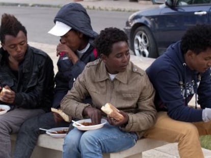 Un grupo de voluntarios ofrece comida a inmigrantes eritreos del centro de internamiento de Lampedusa, Italia.