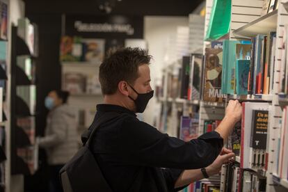 Un hombre busca en una estantería de una librería de Madrid.