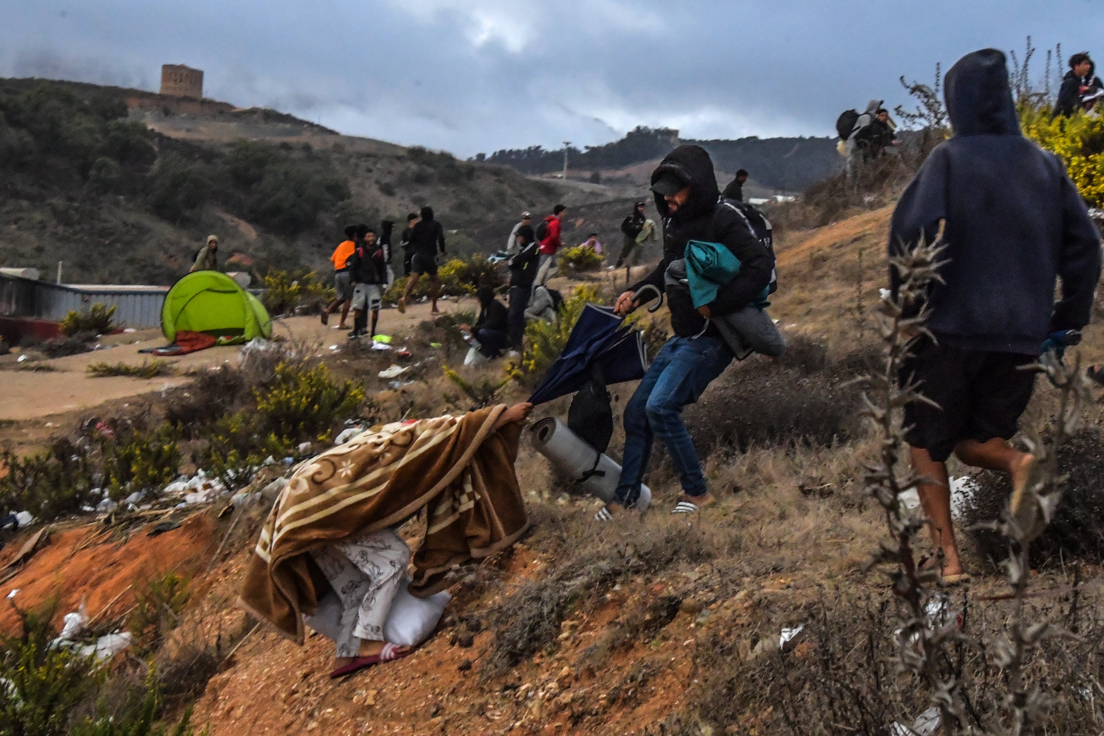 Varios migrantes huyen de la zona del polígono del Tarajal durante el desalojo. 