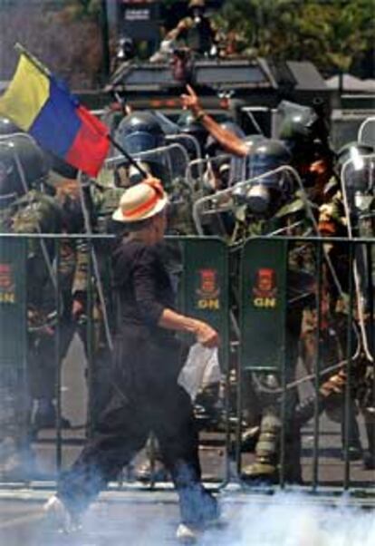 Una manifestante ondea una bandera venezolana frente a un cordón policial en Caracas.