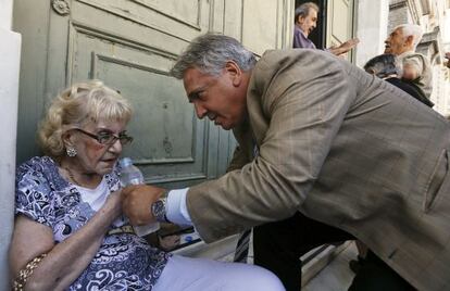 El gerente de un banco ayuda a una mujer que se desmayó mientras esperaba junto a otros pensionistas a la puerta de la entidad.